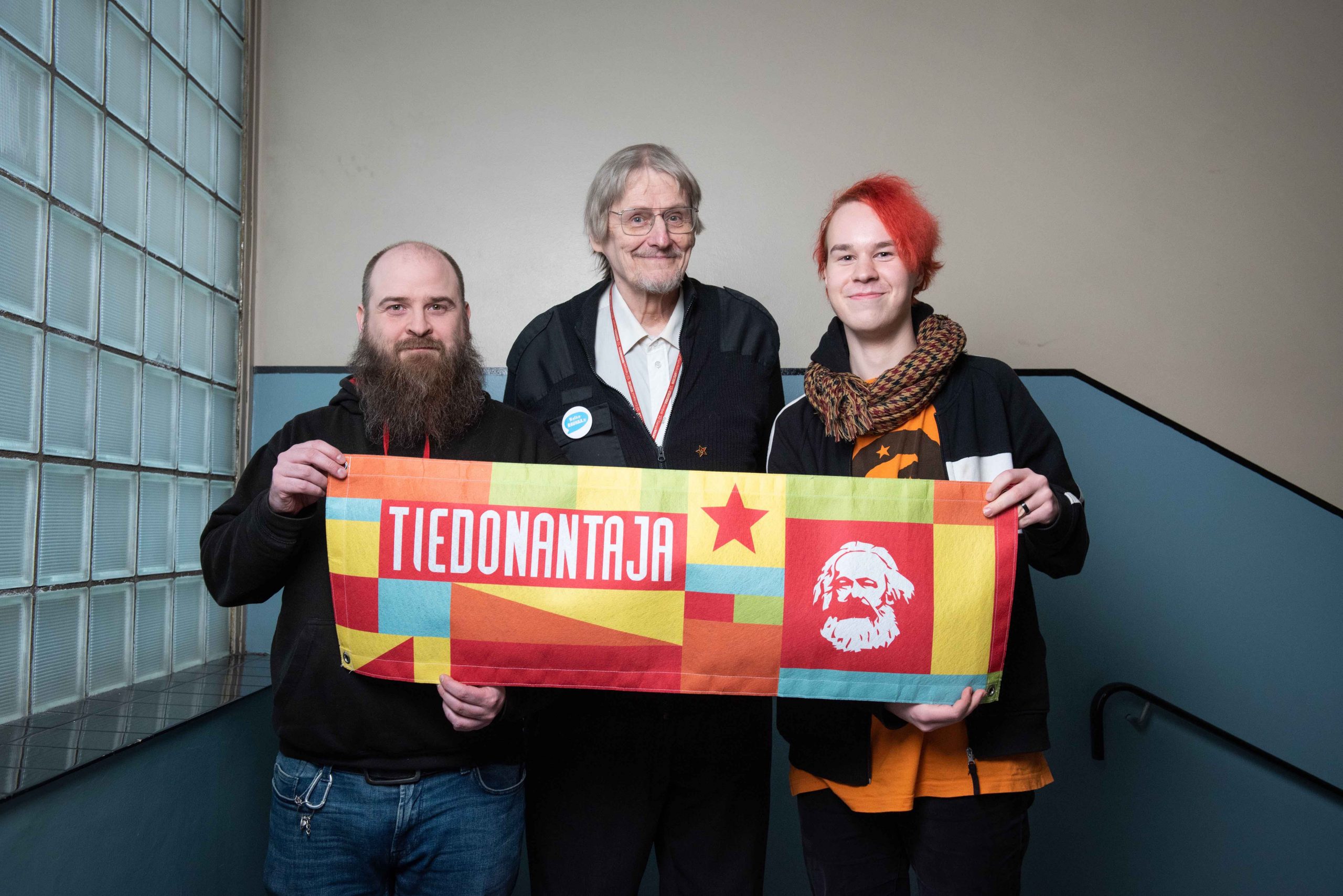 Kolme kommunistia kuvattuna Tiedonantaja-banderollin kanssa.