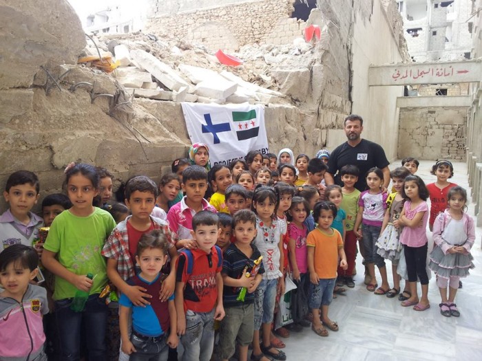 Rami Adham syyrialaislasten kanssa Aleppossa tuhoutuneen koulun raunioilla.
